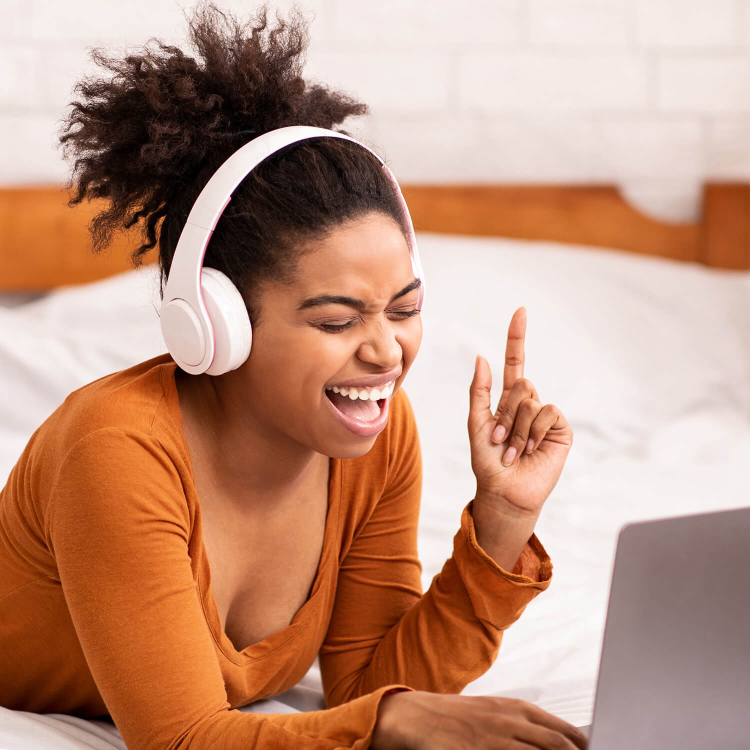 Happy woman with headphone watching a Vala muzi on her laptop while lay on her bed
