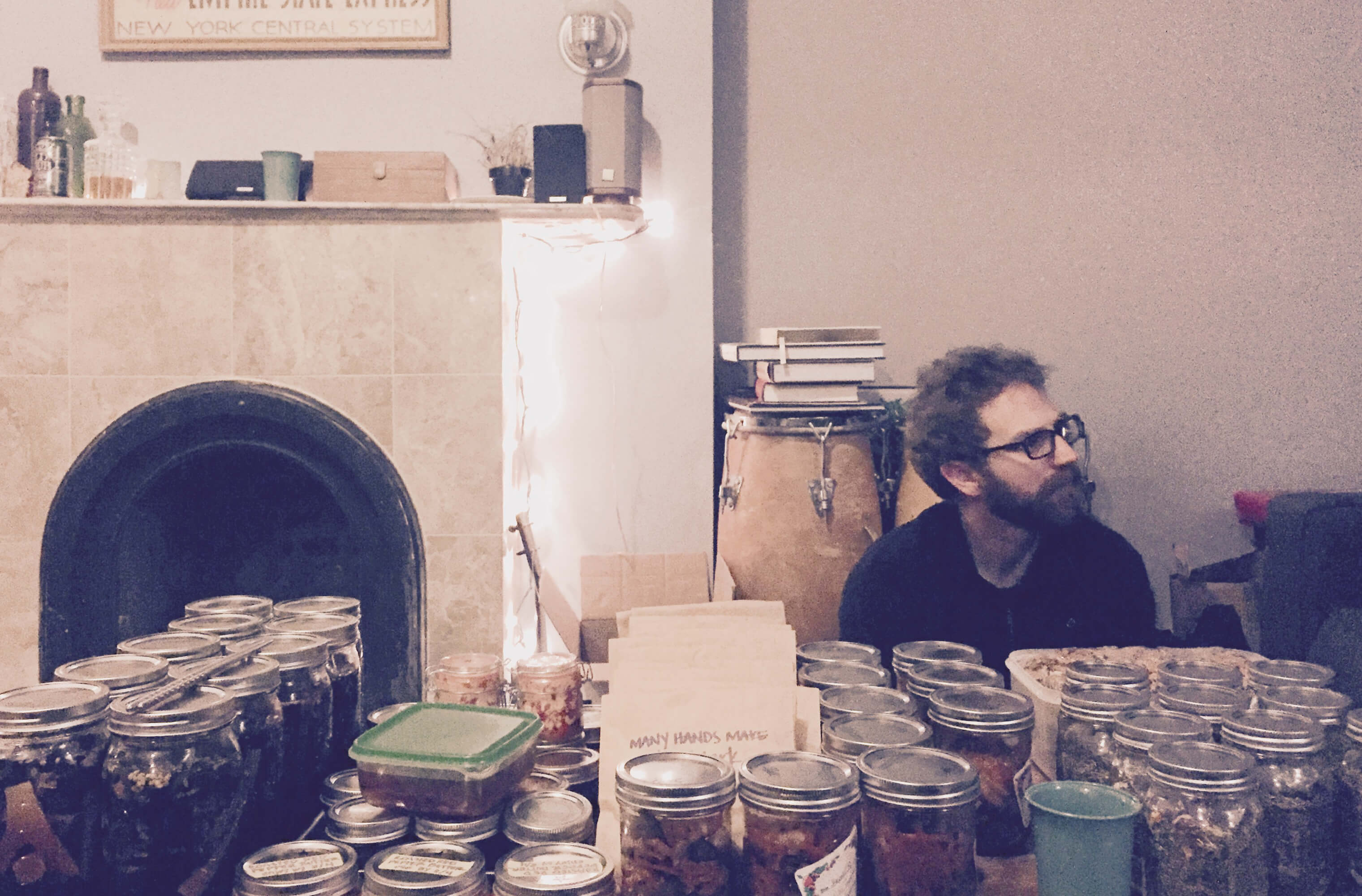 A guest seated behind rows of homemade condiment jars at a Condiments Club gathering