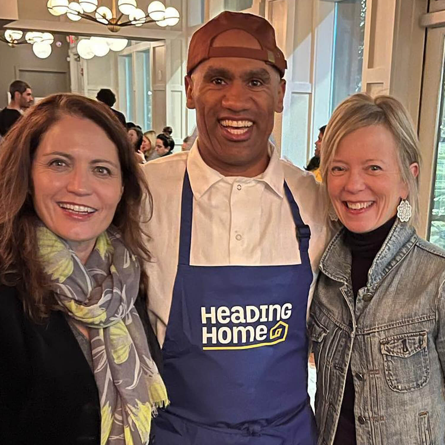 Guests at a Heading Home event and a chef wearing a branded apron