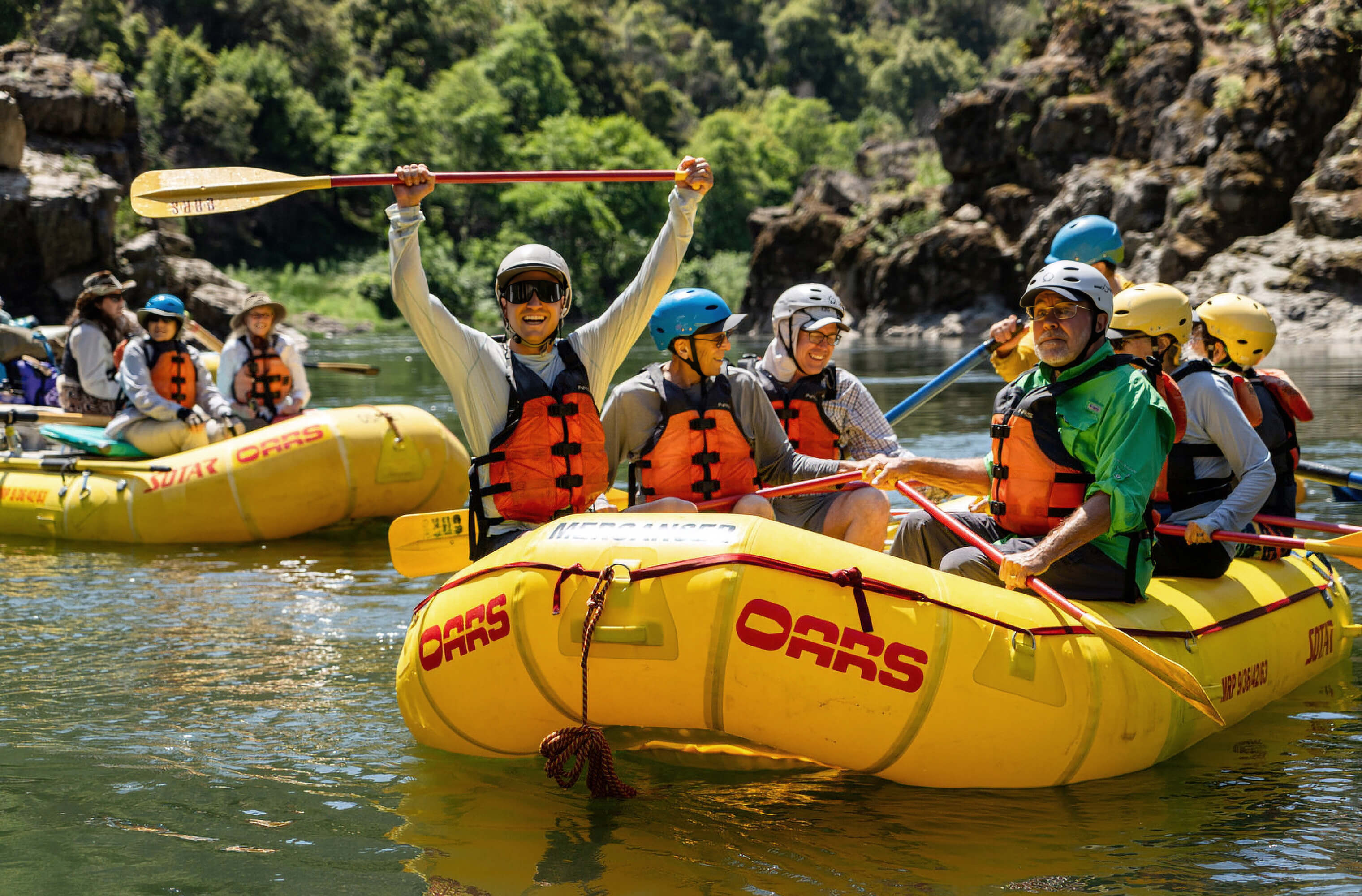 An OARS rafting group celebrating on a calm stretch of river