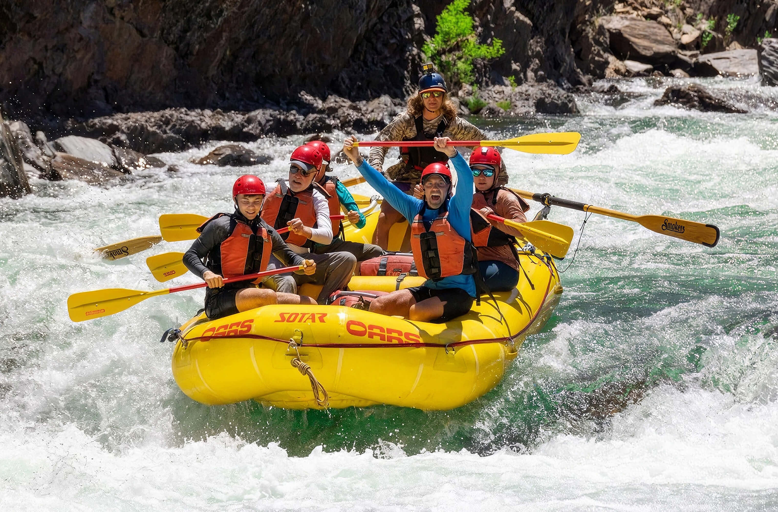 An OARS crew paddling through whitewater rapids