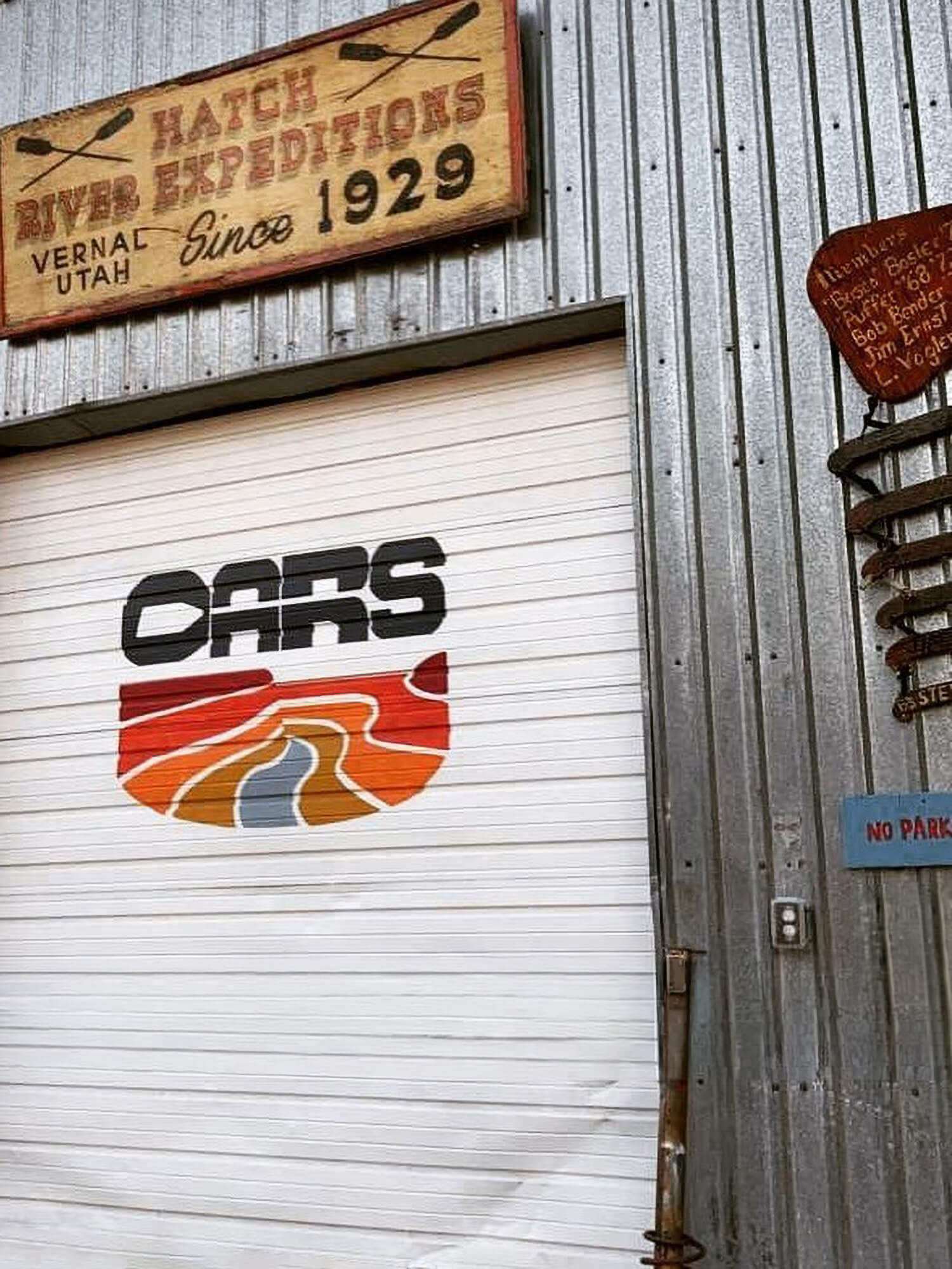 The OARS logo painted on a warehouse door beneath a vintage Hatch River Expeditions sign